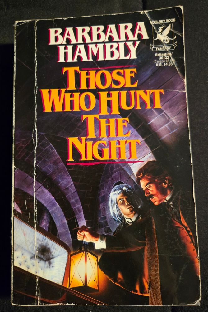 Front cover of Those Who Hunt the Night by Barabara Hambly, showing two men standing over and open coffin, one has dark hair and a mustache and the other has white hair and long fangs.