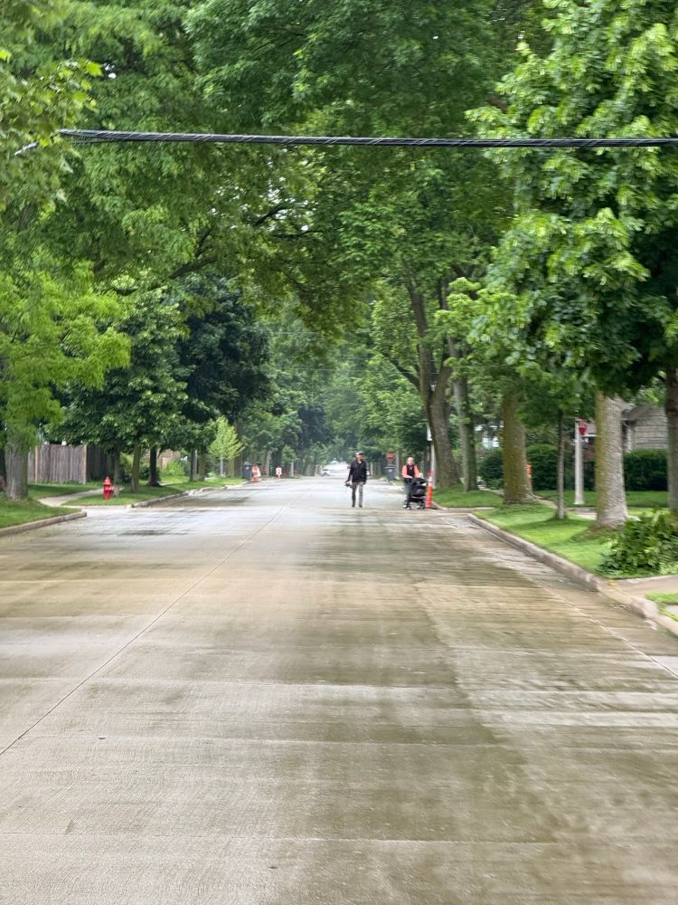 Two people, one pushing a stroller, walking in the street
