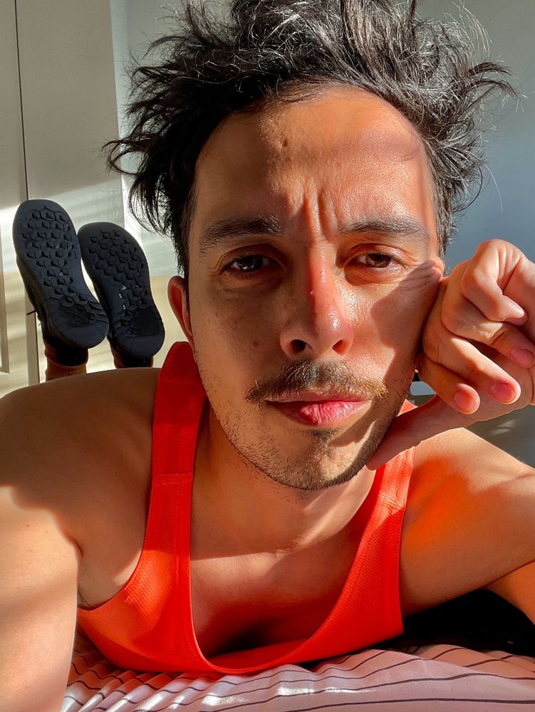 Foreground: Me with sun grazing my left eye’s iris such that its color is highlighted. Background: The soles of my very worn-out but odorless sneakers.