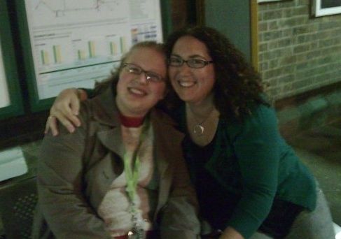 Two woman at Falmer train station, leaning in together and smiling despite the cold weather. The left one is me; the one with her arm around me is Nevvie, who is dearly, dearly missed. 