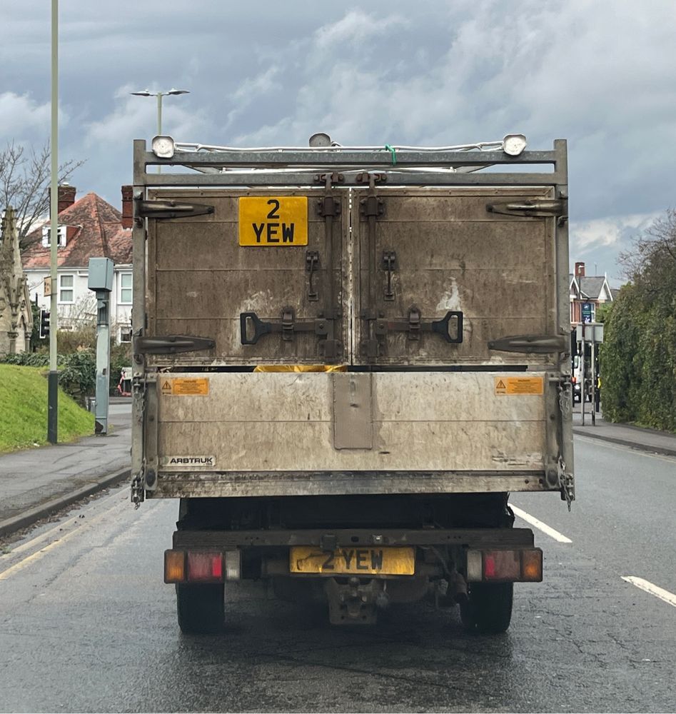 A well-used small truck, of the kind for transporting household or garden waste to a tip, with the number plate 2YEW