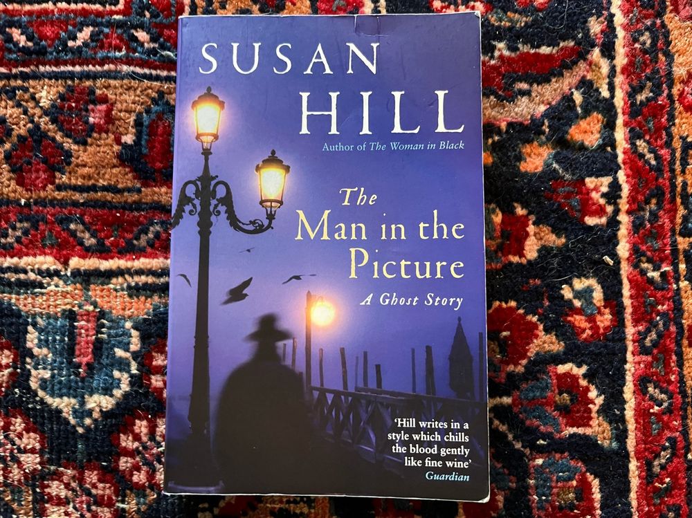 A paperback copy of Susan Hill’s short story The Man in the Picture lies on a slightly threadbare Persian carpet