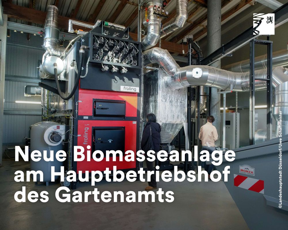 Moderne Biomasseheizanlage mit roten und schwarzen Elementen in einer Industriehalle, zwei Personen inspizieren die Technik.