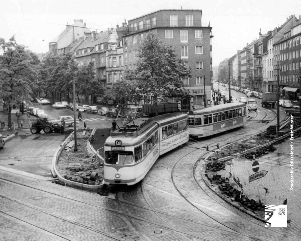 Historische Straßenbahn der Linie U in einer belebten Stadtstraße mit alten Gebäuden und parkenden Autos.
