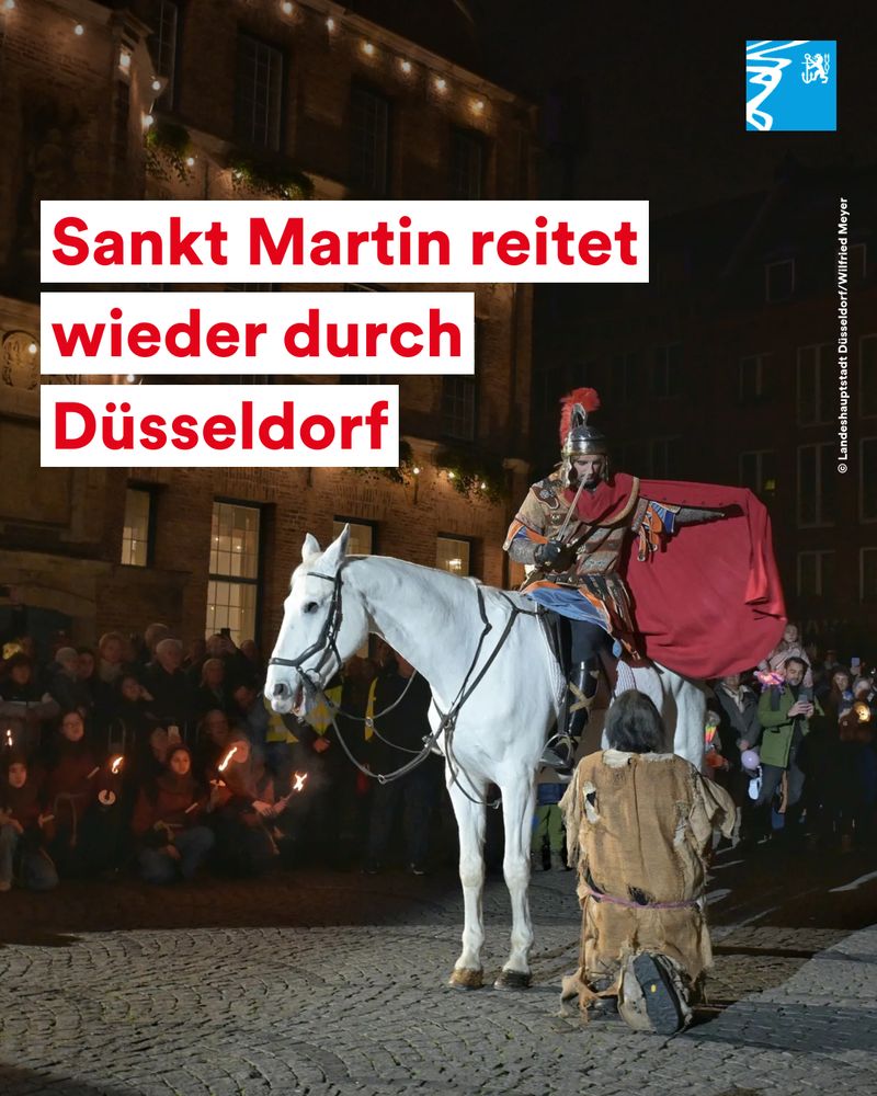 Sankt Martin in historischer Rüstung auf weißem Pferd teilt seinen Mantel mit einem Bettler vor einer Menschenmenge bei Nacht.