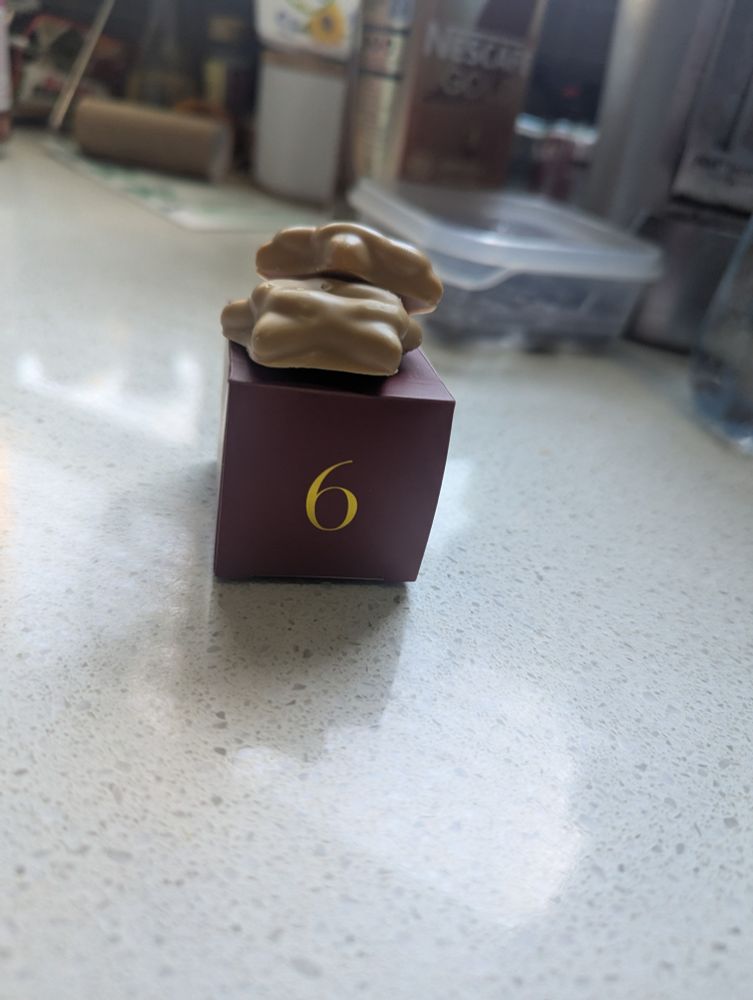 A small red box with a golden six on the front. Sitting on top of the box are 2 caramel covered salted caramel sables that were absolutely delicious 