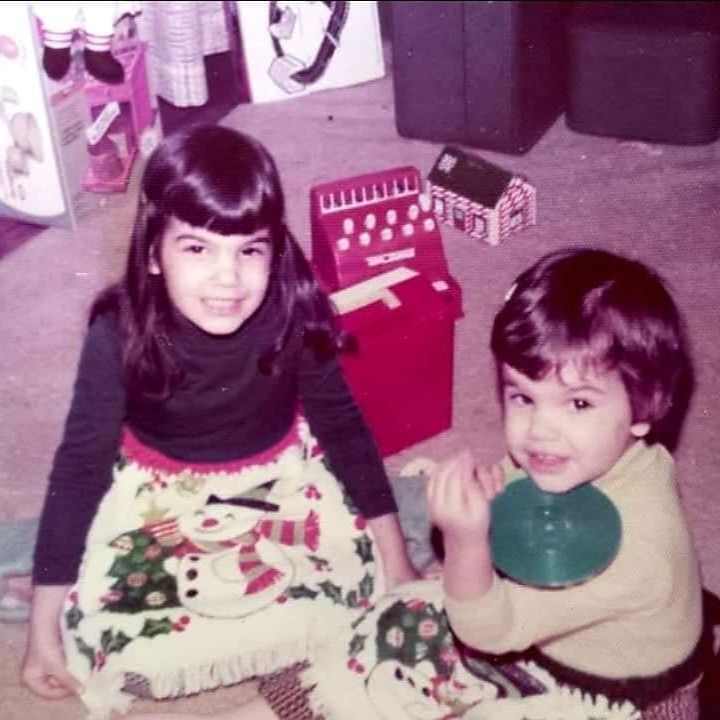 Two girls in a living room on Christmas morning with matching snowmen aprons and toys.