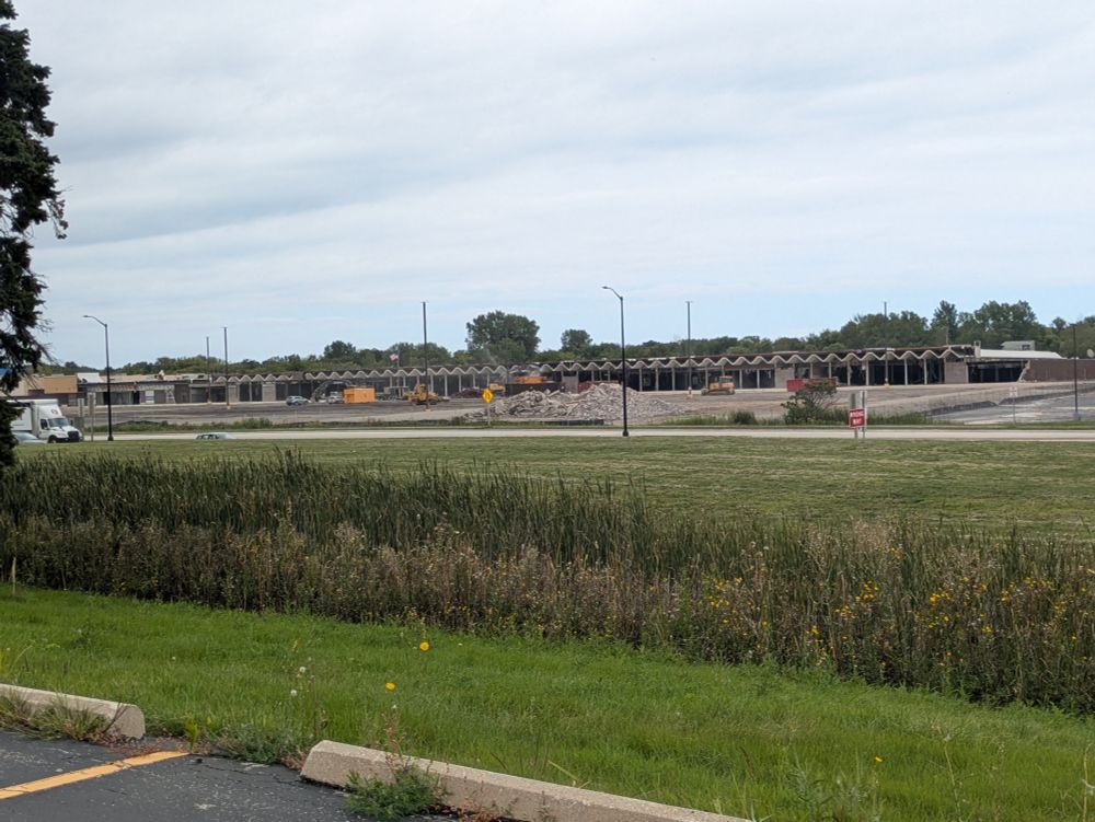A strip mall property in the process of being demolished. The distinctive zig-zag roof of the old Treasure Island stores is visible.