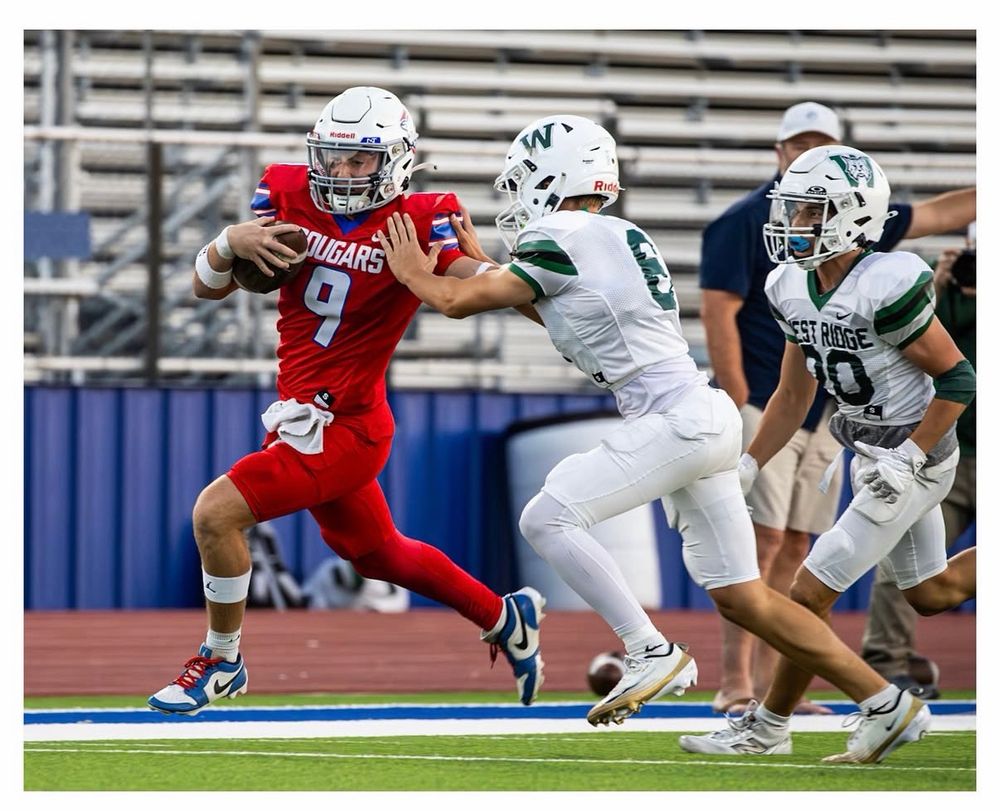 Football player giving a stiff arm to a would be tackler
