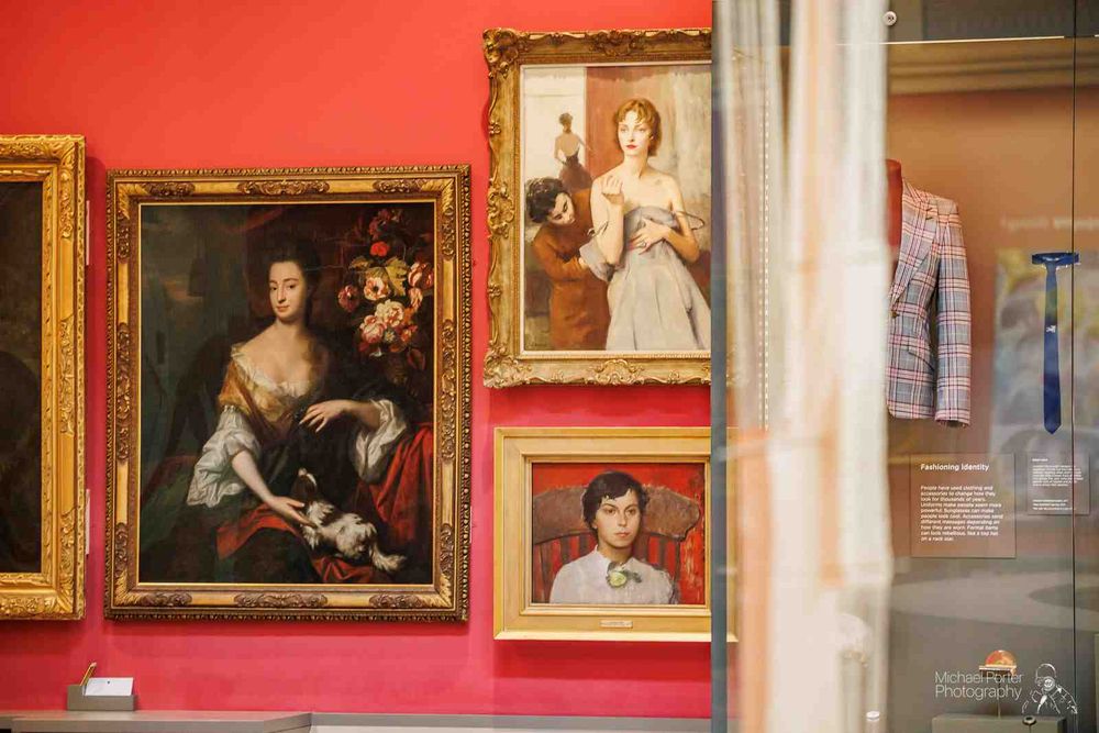 Gallery wall with three framed paintings against a vibrant red background.