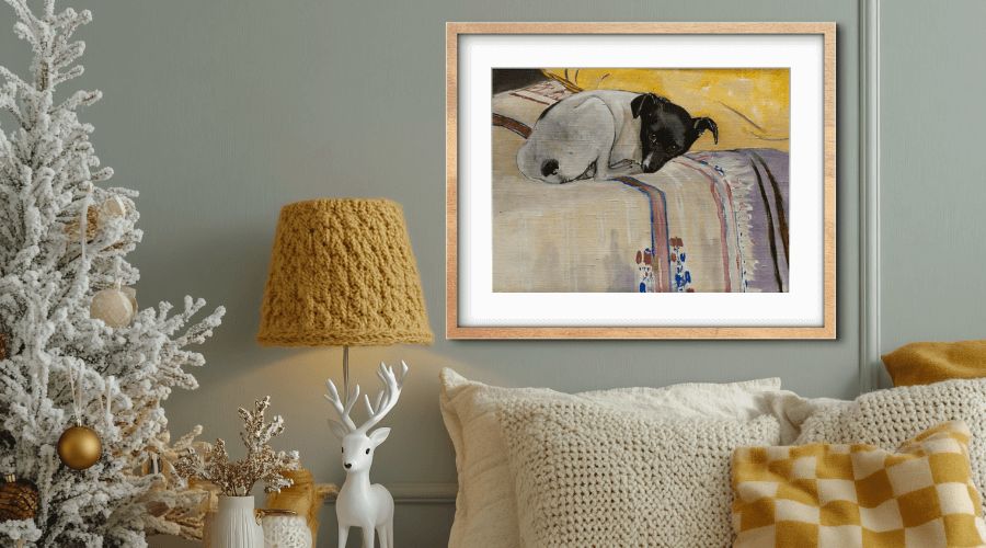 Living room with knitted pillows, a mustard lamp and a framed painting of a black and white dog resting on a striped blanket.
