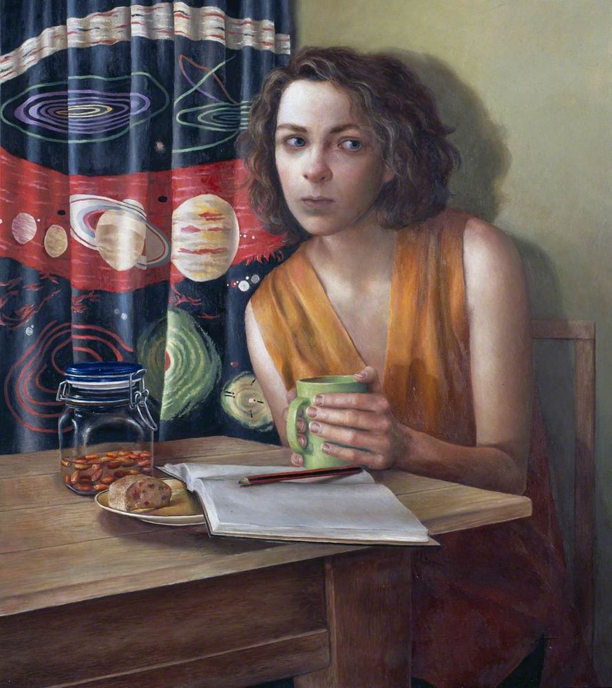Woman in an orange sleeveless dress holding a green mug, sitting at a wooden table with an open diary and pencil, against a backdrop of a colourful solar system curtain.