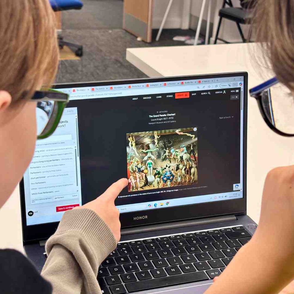 Two people viewing an artwork on a laptop screen.