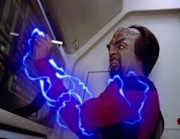 Worf in pain as bright blue electrical energy arcs across his body.