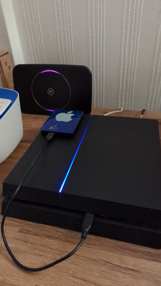 picture of my home server setup - a PlayStation 4! it is connected to a WD My Passport external USB disk with an Apple sticker on it, and a BT Hub via ethernet