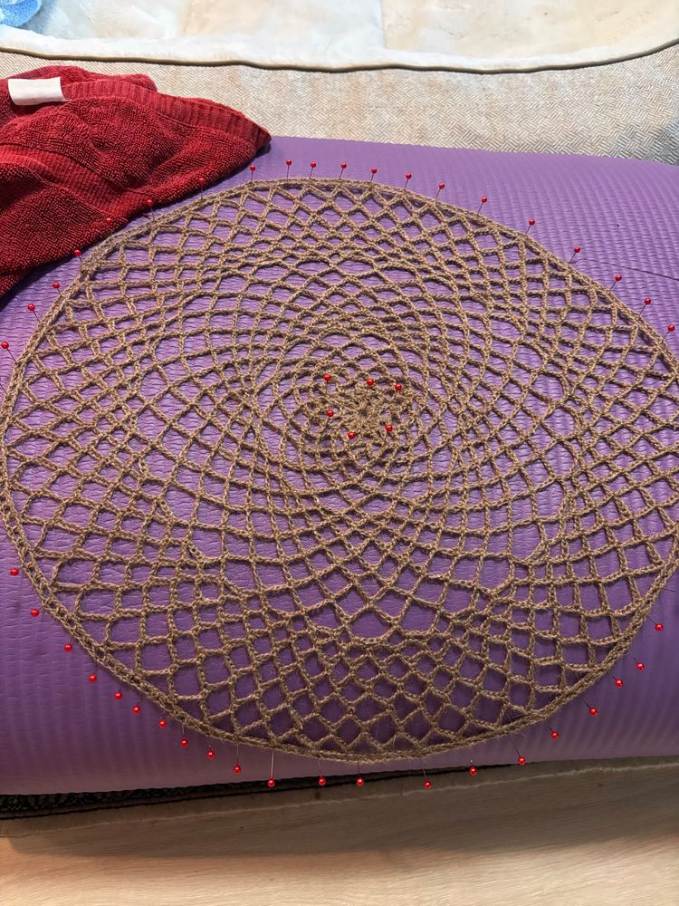 A snood (hairnet) in brown, crocheted and blocked on a mat