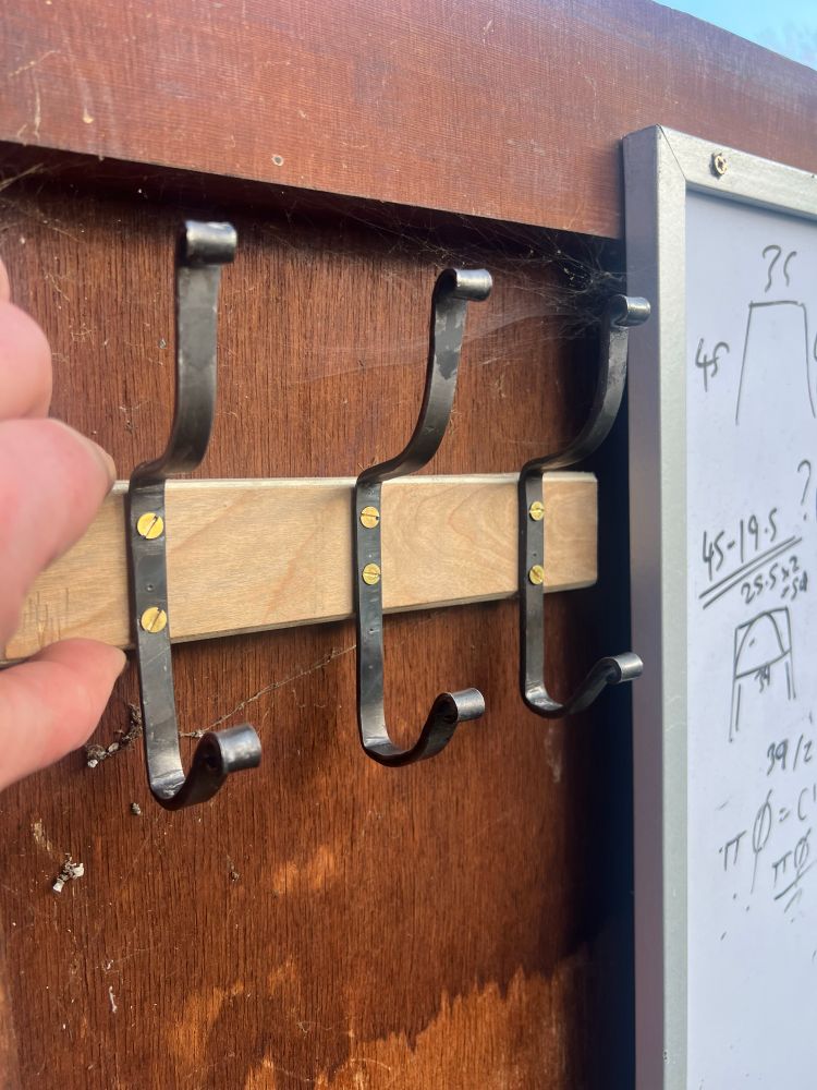 Three double coat hooks in mild steel, the ends of each hook scrolled, and mounted using brass screws to a plywood plinth. Which is very nice to say aloud. Try it. Plywood plinth. Plywood plinth. Anyway, they look great and as soon as I can lay hands on a new batch of this metal (trickier than you might imagine) I shall be making some more. 