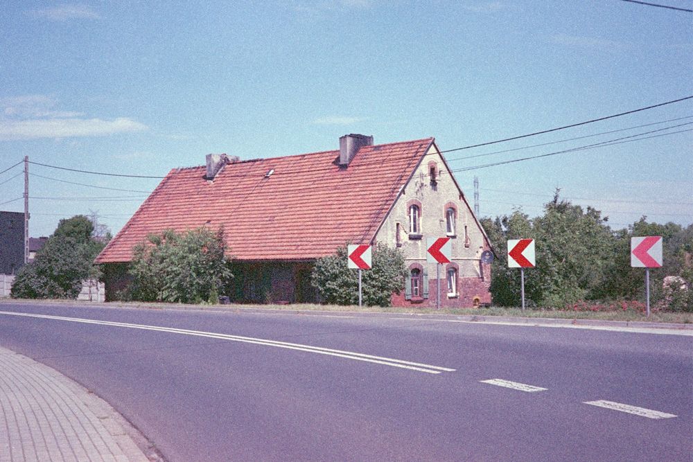 an old house seen from across the street, behind some roadsigns and a bit below the road level