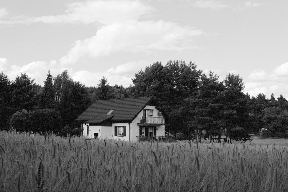 a single white house between some trees and a field