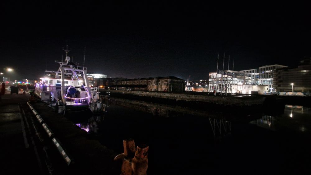 Christmas lights in the form of a tree on the stern of a survey boat. Im the background the Port of Cork bonded warehouses and the Horgan's Quay development 