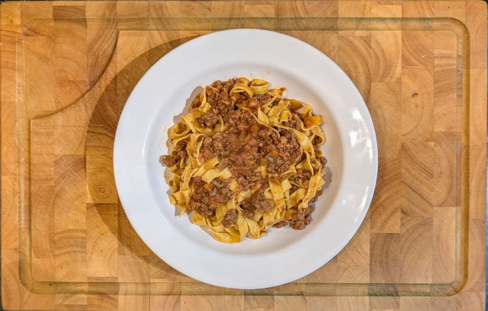 Photo of a bowl of tagliatelle con Ragu alla Bolognese. Ribbons of pasta mixed with a rich, thick meat sauce. 