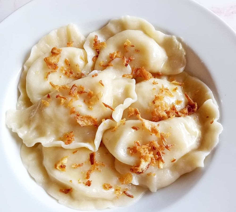 Plate of pierogi topped with crispy onions 