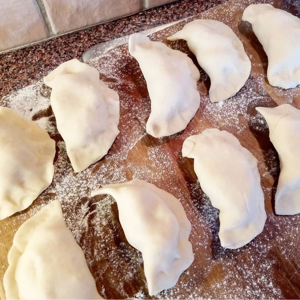 Uncooked pierogi on a wooden board