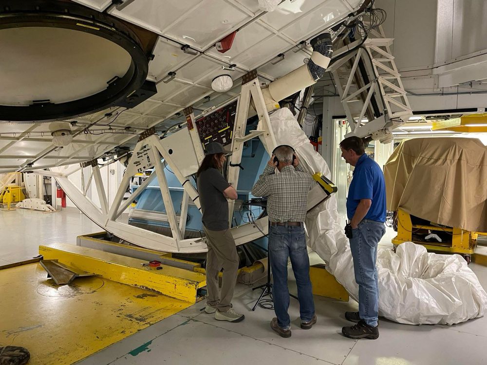 Engineers stand next to the telescope with headphones. They are listening to a recording of the telescope’s natural vibrations and the motors.