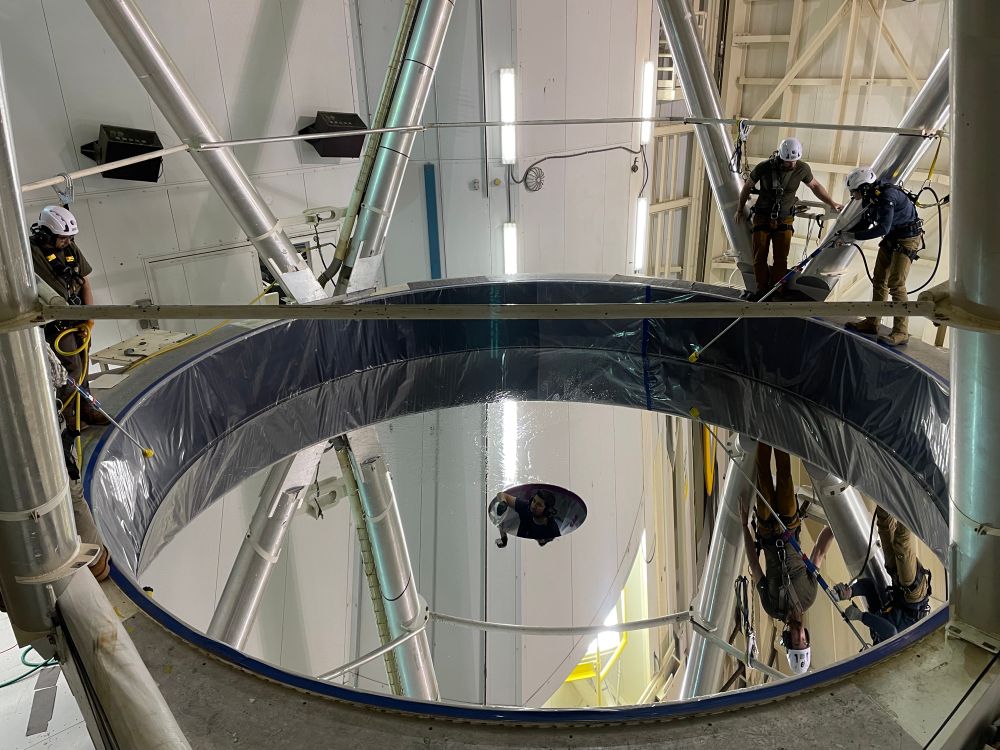 The mirror is dried with long air wands to prevent streaking. Someone stands in the central hole to soak up excess water with non-scratch material. 