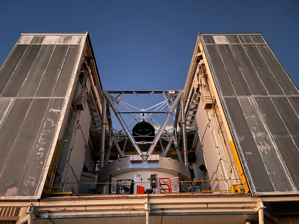 The MMT telescope is open and pointed at a dark blue sky