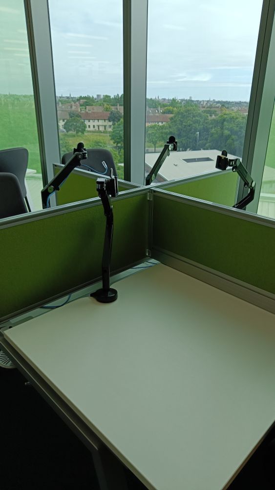 Empty desks with monitor arms protruding upwards but the computers are gone, in front of a window looking out across Aberdeen 