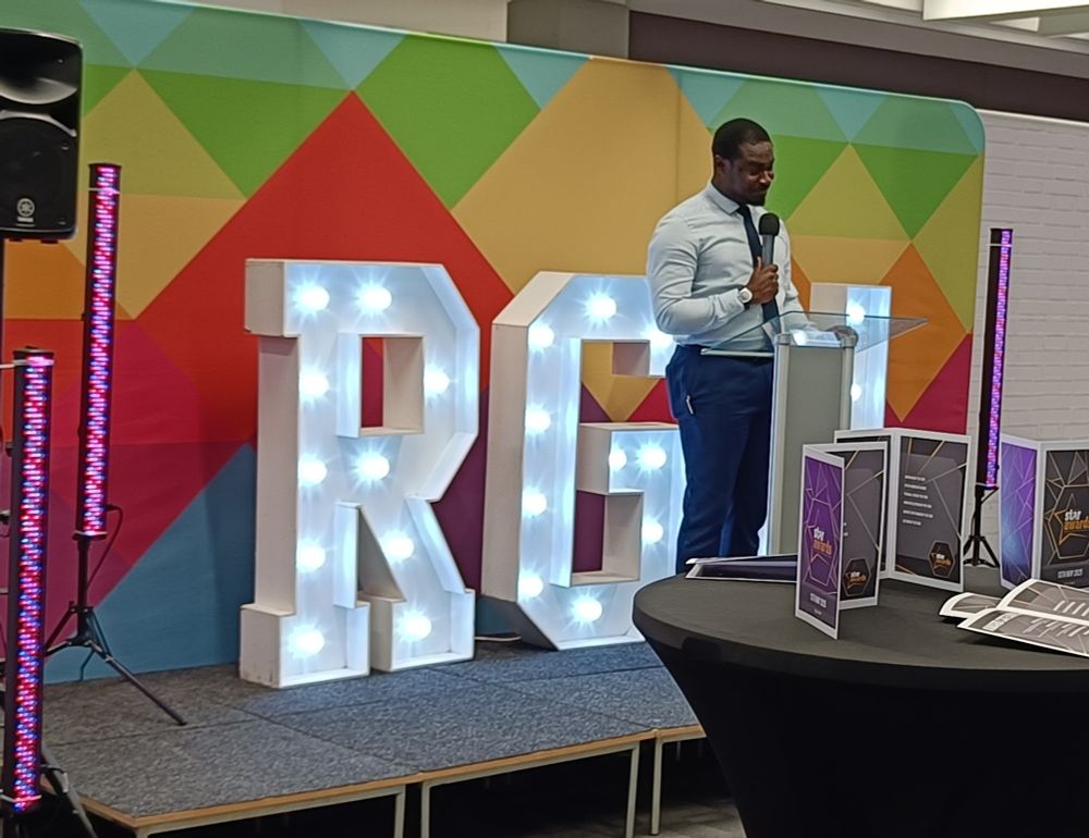 Seth Odei Asare on stage introducing the Star Awards in front of the RGU initials in lights