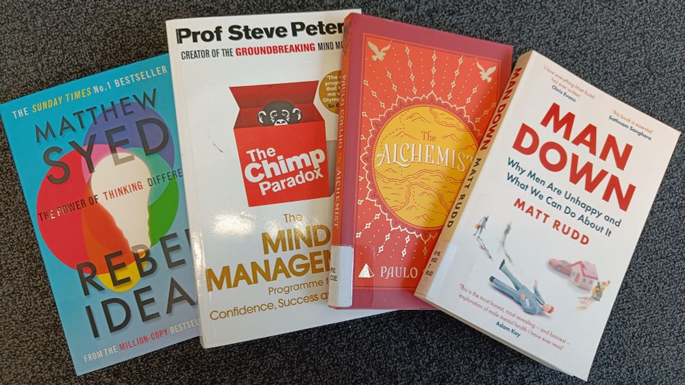 A selection of colourful books to support our mental health, including "Man Down"