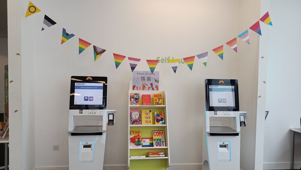 Pride banner above a book display of relevant books and our self issue machines