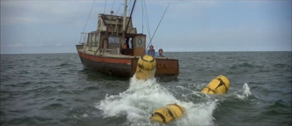 Sheriff Brody (Roy Scheider), Matt Hooper (Richard Dreyfuss) and Quint (Robert Shaw) aboard the Orca watch as three yellow barrels attached to Bruce the great white shark break the surface of the water. 