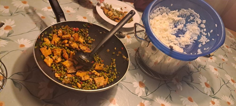 a strainer filled with rice & a wok with tofu, peas and a lot of niceties for taste