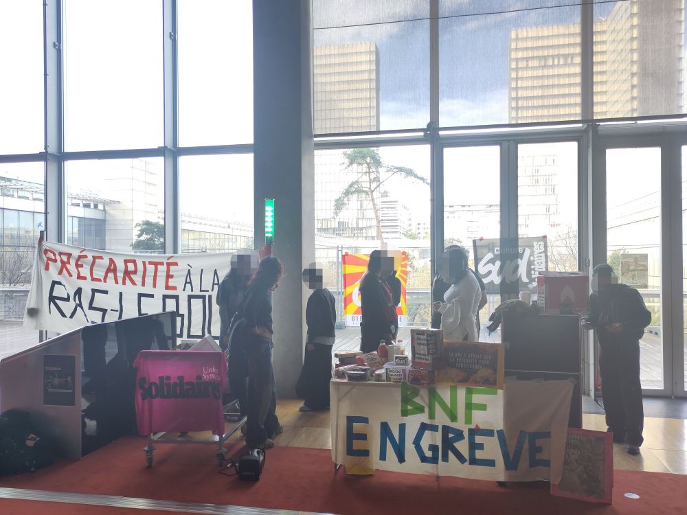 Piquet de grève dans le hall de la bnf, avec banderole "précarité ras le bol" et "BNF en grève" 