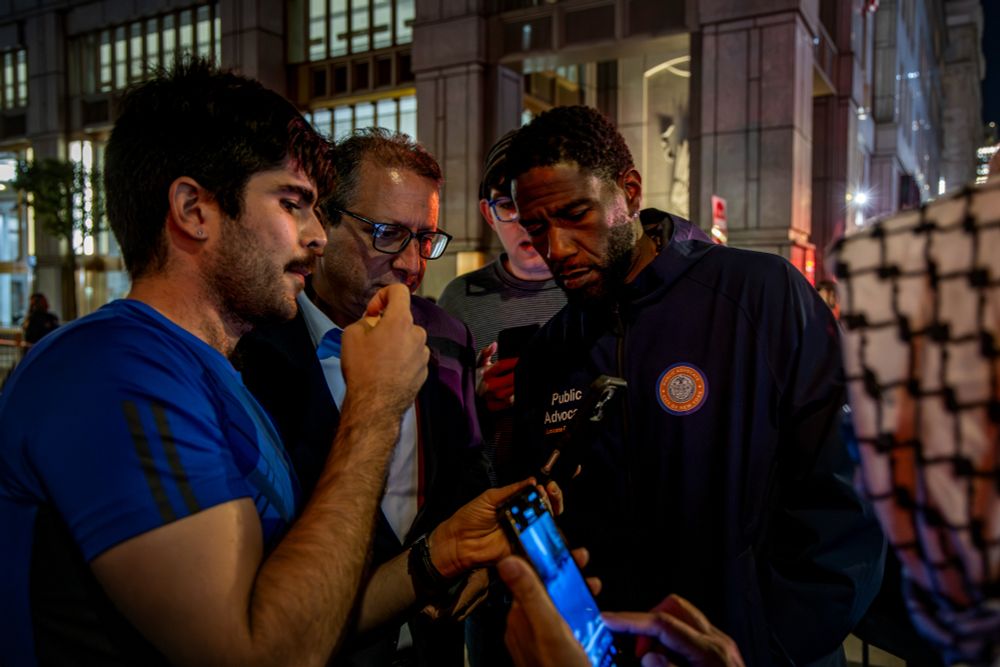 The Public Advocate and Comptroller look at phone footage taken by protesters