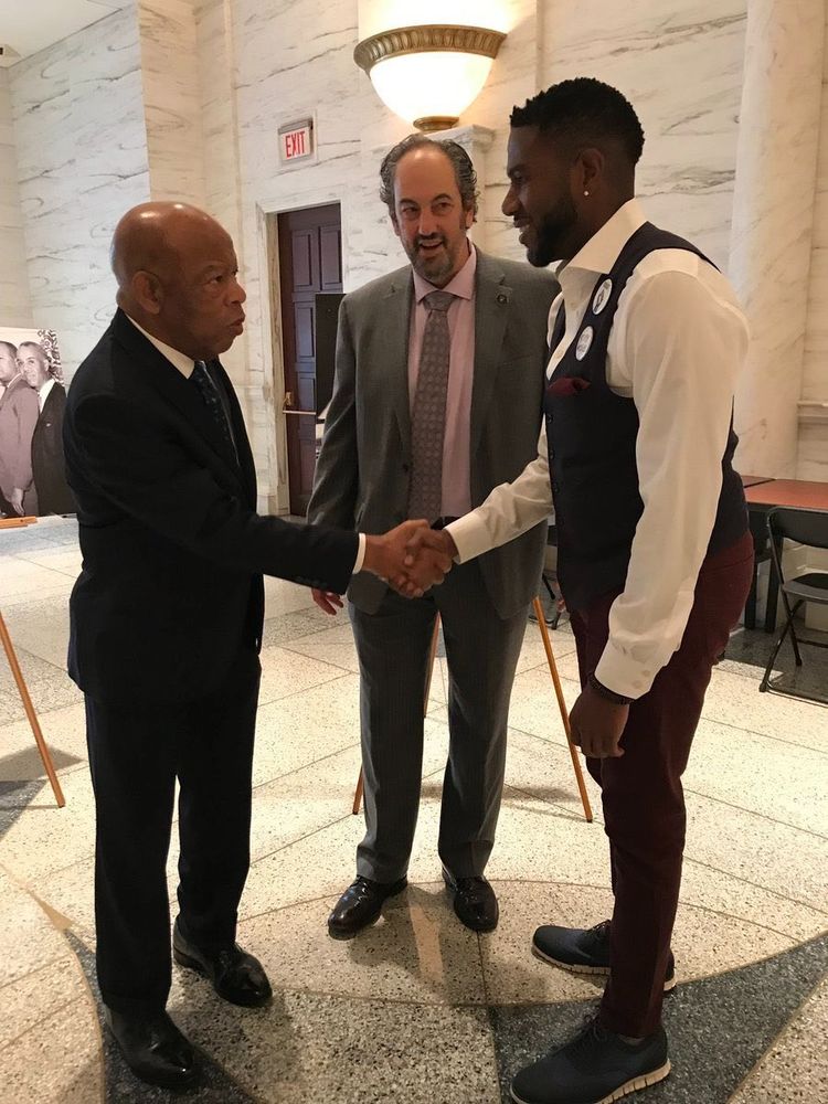 An older photo in which the Public Advocate shakes the hand of Congressman John Lewis