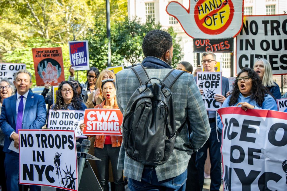 The Public Advocate photographed from behind, turns around to face rally attendees as they chant