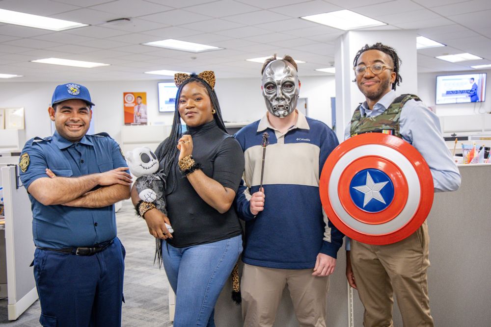 Staff members wear a Raccoon Police costume, a cat costume, a silver mask, and a Captain America costume