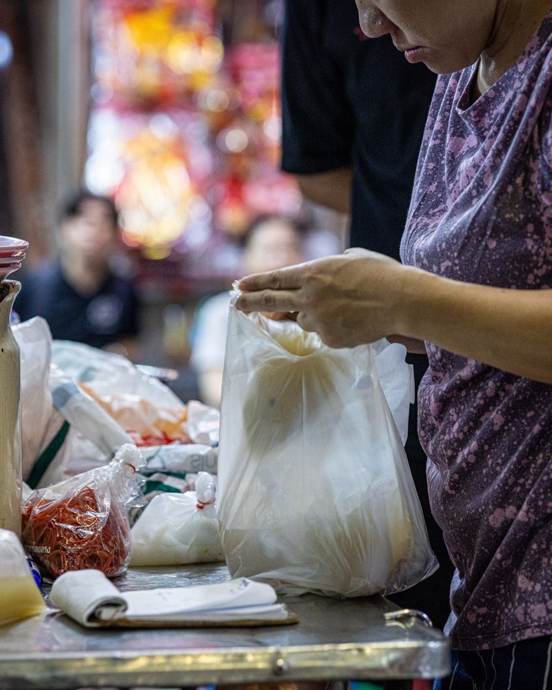 Person putting food into a plastic bag.