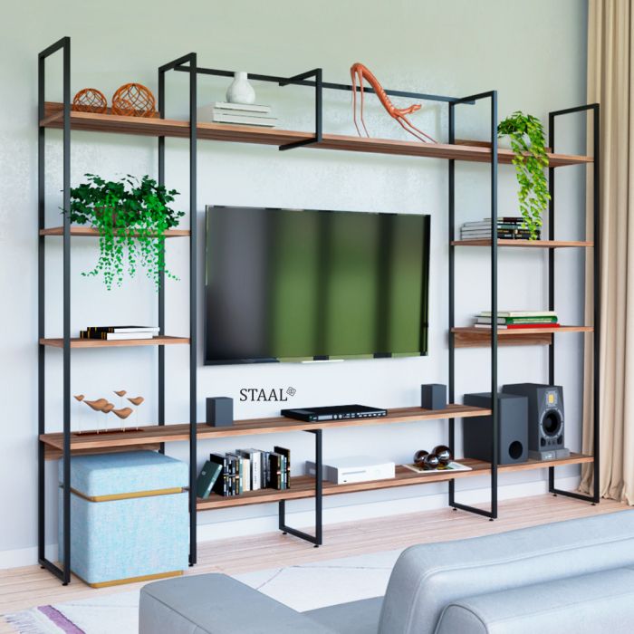 estante moderna de metal preto com prateleiras de madeira envolve uma TV de tela plana

nas prateleiras há plantas pendentes, livros empilhados, caixas decorativas, esculturas e objetos de design minimalista

embaixo da TV ficam dois alto-falantes e aparelhos eletrônicos, e à esquerda um puff azul claro com detalhes dourados