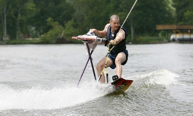 A man in a life vest is attempting to iron a shirt while water skiing in an example of extreme ironing.