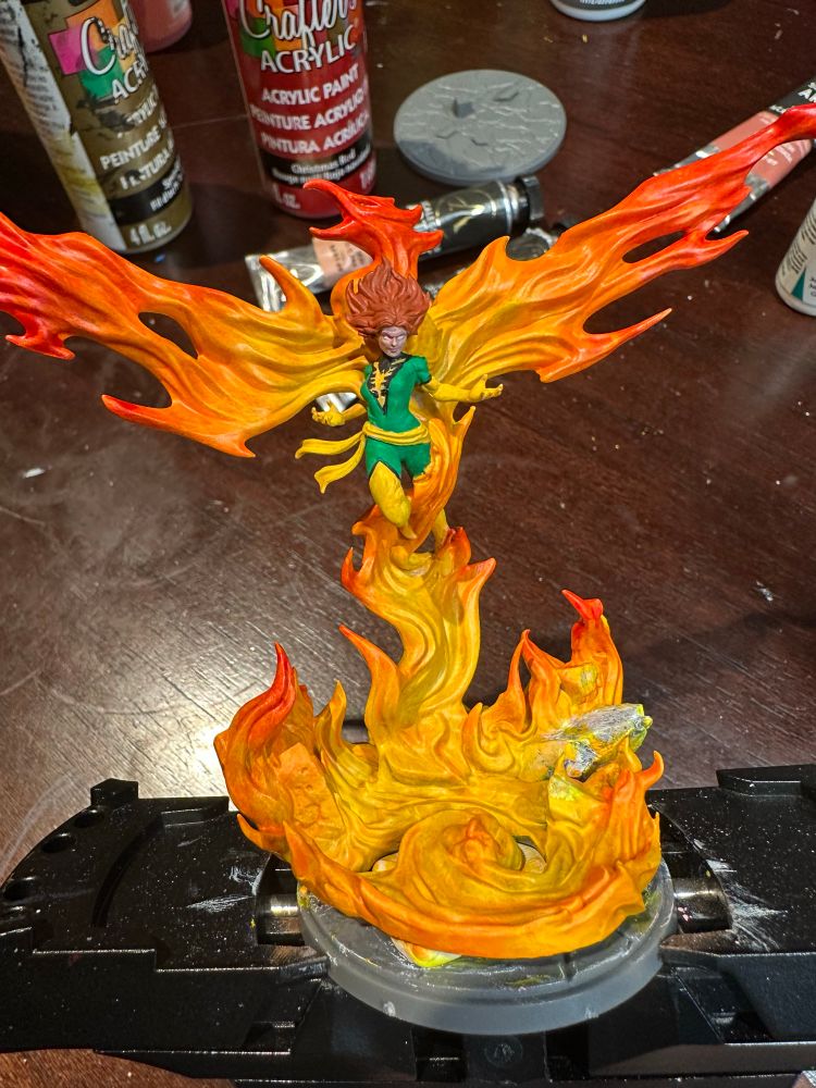 Mostly painted model of Phoenix Unleashed from Marvel Crisis Protocol
A woman wearing green and yellow rising from bird-shaped flames