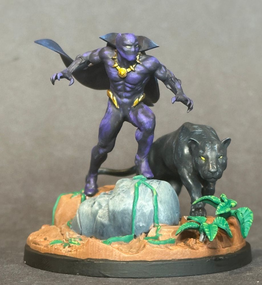 Painted miniature of Black Panther. Classic costume with dark purple highlights and dark blue cape.

He’s standing on a stone gorilla head with a panther walking next to him
