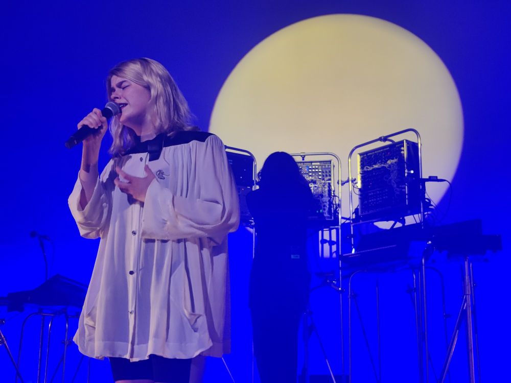 Zaho de Sagazan on stage lit in vivid blue and yellow