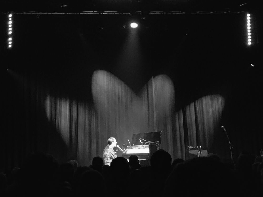 A black and white image of Joan as Policewoman on stage at the piano, seen from distance.