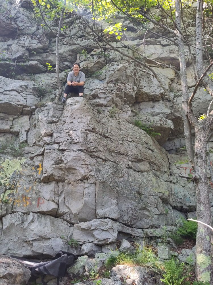 Crash pad at the bottom and climber turned toward the camera on acliff