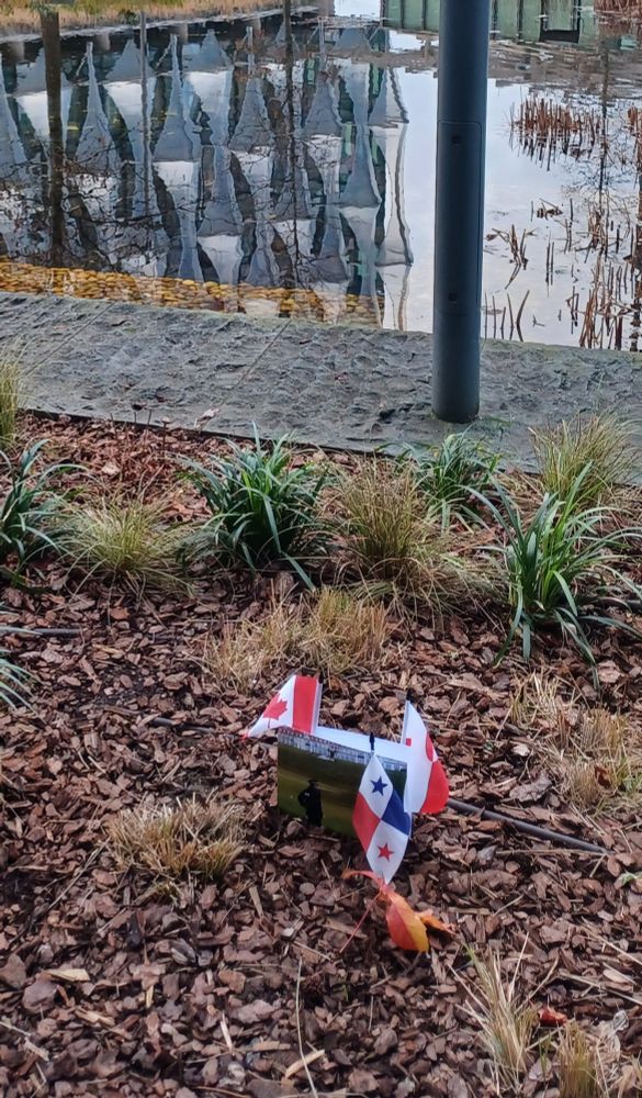 Greetings card and flags (Canada, Panama, Greenland) in a flowerbed outside the US embassy